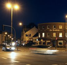 Nachtbild der Verkehrskreuzung vor dem Restaurant 'Zur Trotzburg' mit vorbeifahrenden Autos.